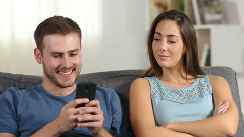 Jealous wife scolding her husband who is using a smart phone at home