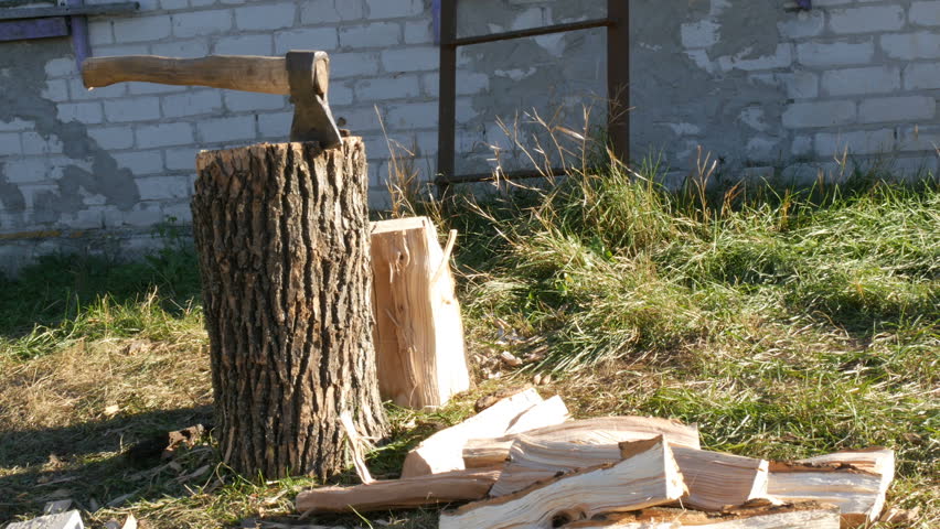 Large village ax sticking in a tree stump and firewood near Royalty-Free Stock Footage #1018263751