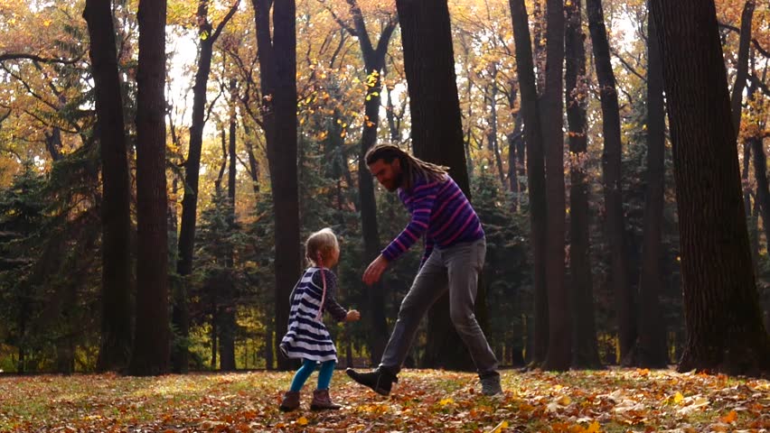 Dreadlocked father plays with his little daughter in the autumn forest | Shutterstock HD Video #1018264852
