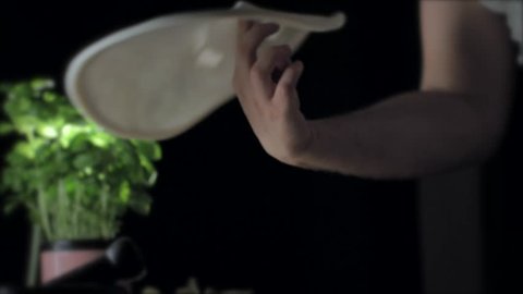 Closeup shot of hands of professional pizzaiolo spinning and tossing pizza dough