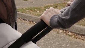 Hands of a mother strongly holds baby pram slow motion video