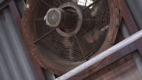 Slow motion clip of an old and rusty cooling fan while rotating.