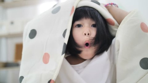 4K Slow motion of Cute little Asian girl covers with blanket. Playing hide and seek, peek a boo