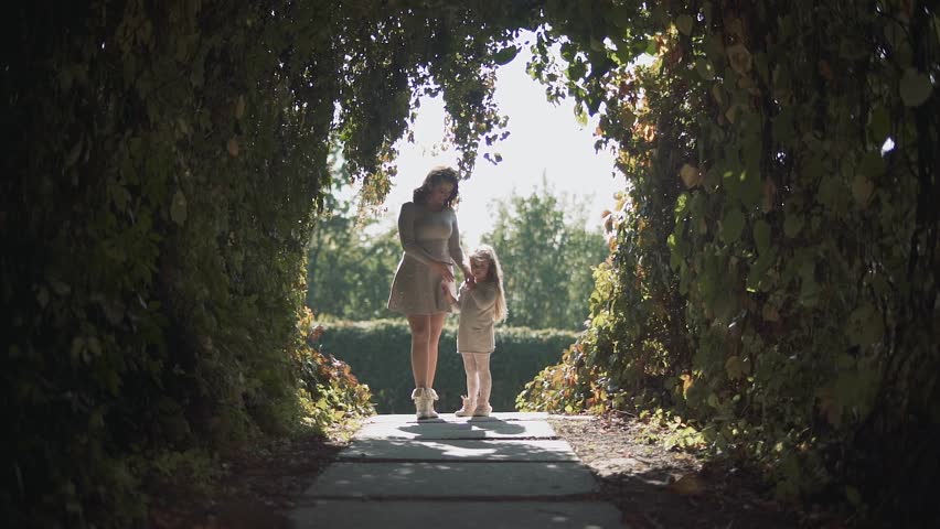 Mom and daughter in a tunnel of bushes