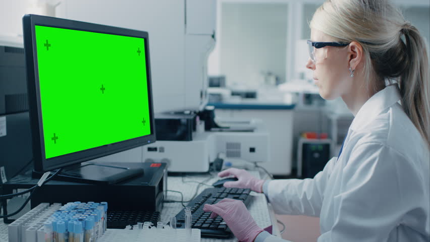 Female Research Scientist Sits at His Workplace in Laboratory, Uses Green Mock-up Screen Personal Computer. I the Background Genetics, Pharmaceutical Research Centre. | Shutterstock HD Video #1018299520
