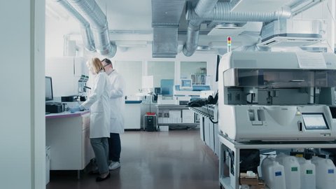 Time Lapse Shot of Team of Research Scientists Working On Computer, with Medical Equipment, Analyzing Blood and Genetic Material Samples with Special Machines in the Modern Laboratory.