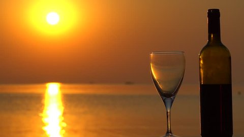 Glass And Wine Bottle At Seaside With Sunrise Background