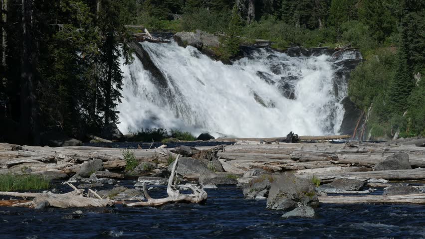 Steady wide shot of the water cascading down Lewis Falls at the Yellowstone National Park, Wyoming, with natural sounds of the water.