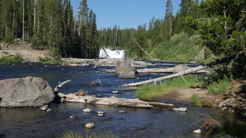 Wide steady shot of the Lewis Falls and Lewis River at Yellowstone National Park in Wyoming, with natural water sounds.