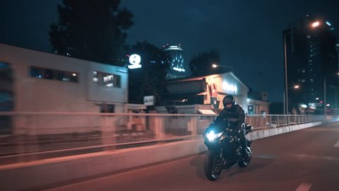 Bucharest, Romania-09.20.2018: Moving tracking shot driving riding suzuki gsxr motorcycle bike rider on a bridge night city street rolling skyline