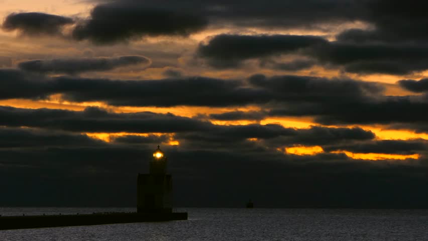 Dramatic dawn over harbor With majestic lighthouse, breathtaking time lapse sky and clouds.