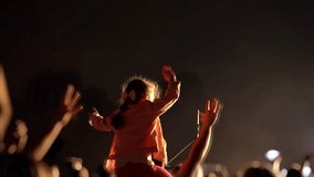 Little girl watching a concert on her father's shoulders. Happy people are watching an amazing musical concert. Merry fans jump and raise their hands up. - Powered by Shutterstock - Get 15% off with code: PIKWIZARD15