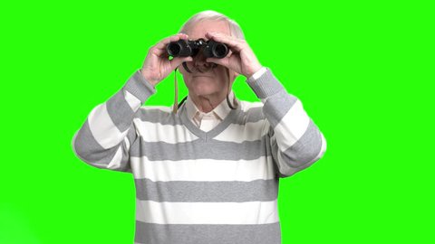 Old man looking through binocular. Grandpa with binocular, green hroma background.