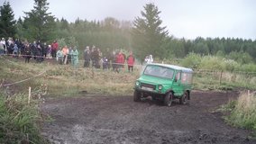 Off-road riding through muddy puddle on dirt road, with large splash during competition jeep. Clip. Concept of extreme driving. SUV speed enters into a muddy puddle