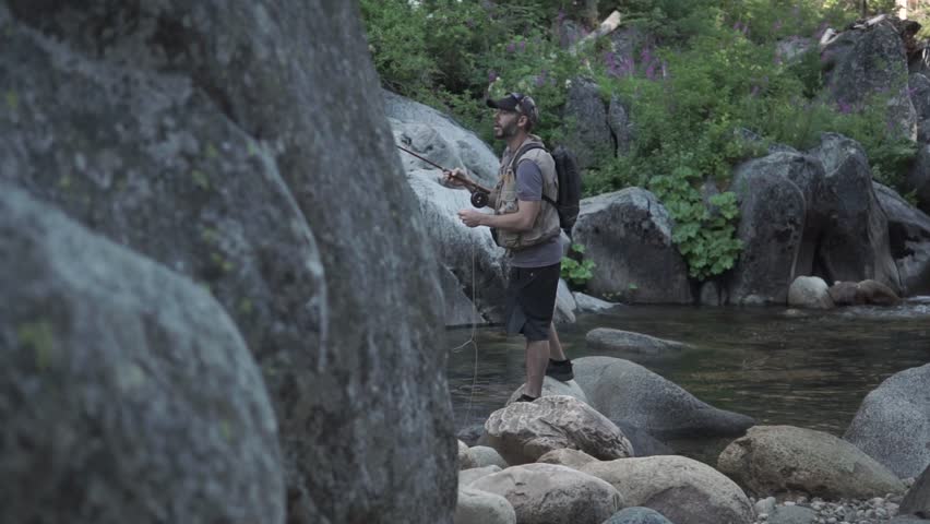 Slow reveal of middle-aged man fly fishing in Dinkey Creek, California, in the Sierra Nevada mountains.