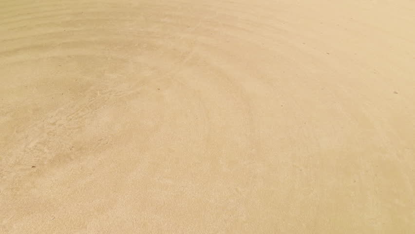 Big dreams come from humble beginnings. Drone ascension over small, baseball field with circular pattern and footprints in infield silt and sand. Basic dugout and whole field present.