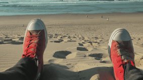 Relaxing man in red sneakers on the blue beach backgrond