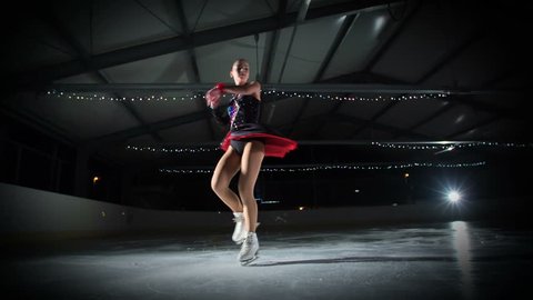 An elegant figure skater is having a beautiful performance in the ice rink.