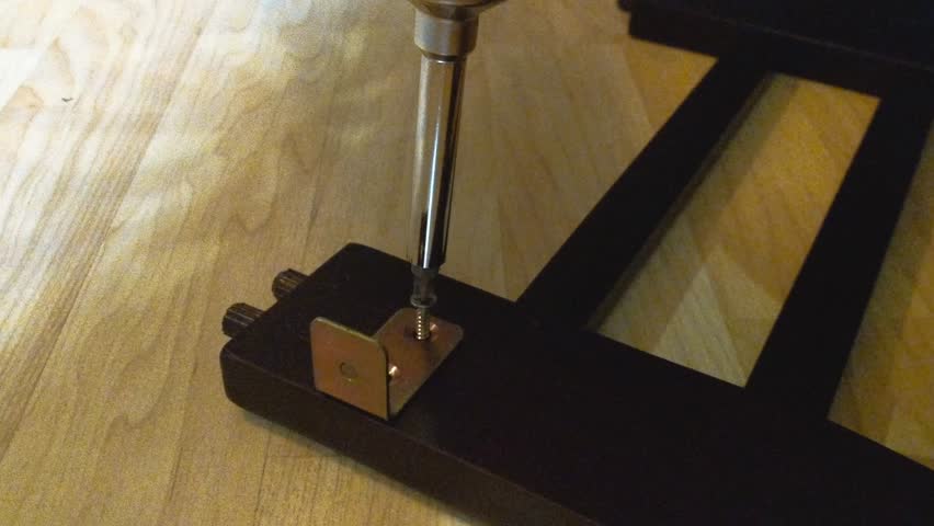 Screw driver twisting screw into wood