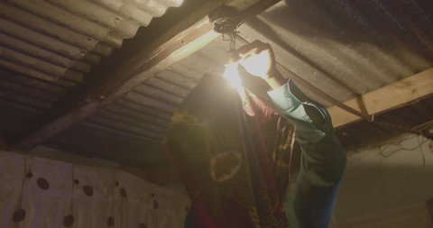 A man fixing his light bulb in his home in the township of Livingstone.