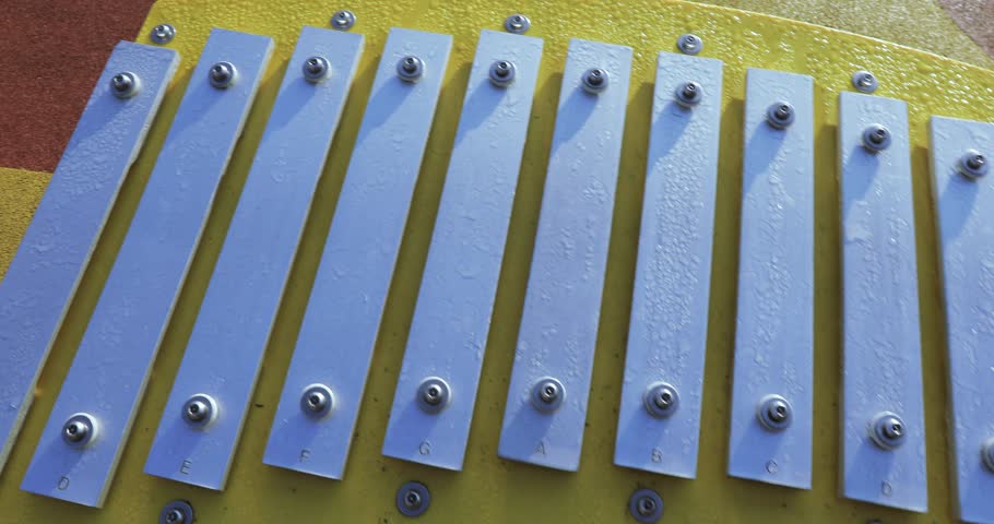 Playing on the metallophone in the light of the morning sun in the city park of South Butovo
