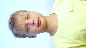 Closeup portrait of happy little european kid isolated on blue sky background on summer beach during sunset time. Vertical orientation video of boy counting from 1 to 5 with fingers, giving thumb up.