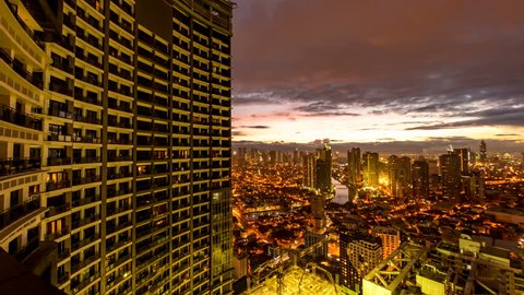 METRO MANILA, PHILIPPINES - CIRCA MARCH 2018: Spectacular time-lapse view on high rise condo buildings in Makati by the River Pasig as the traffic passes on congested road at the foot of illuminated s
