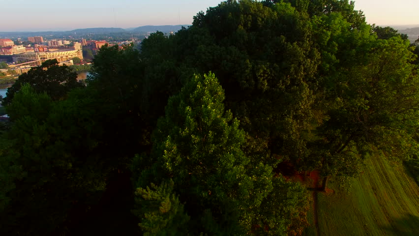 Slow reveal of the Knoxville skyline at sunrise over the trees of Fort Dickerson.