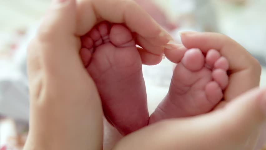 Baby feet in mother hands. Tiny Newborn Baby's feet on female Heart Shaped hands closeup. Mom and her Child. Happy Family concept. Beautiful conceptual video of Maternity. Royalty-Free Stock Footage #1018363966