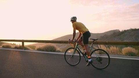 The athlete on a Bicycle goes from a rock on a mountain serpentine looking at a beautiful view of the island. The concept of a healthy lifestyle