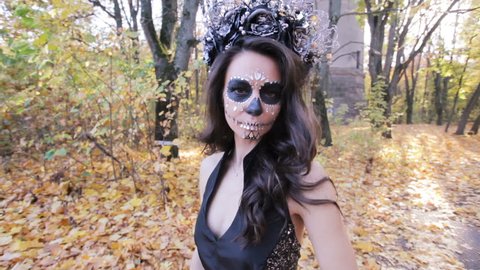 Portrait of a beautiful zombie girl with a wreath on her head, she is in the autumn forest.