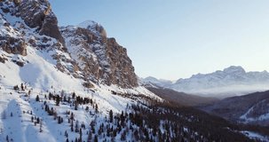 Side orbit aerial to snowy valley with woods forest at Falzarego pass.Sunset or sunrise, clear sky.Winter Dolomites Italian Alps mountains outdoor nature establisher.4k drone flight