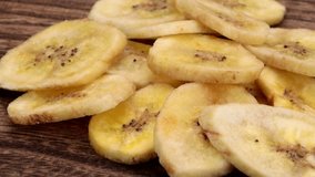 Dried banana chips rotate on wooden plate