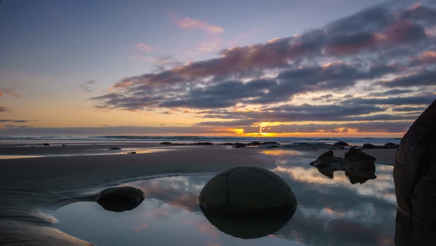 Beautiful Sunrise At Moeraki Boulders- Timelapse Zoom Out Right.
Moeraki Boulders are a group of large spherical stones that have been exposed through shoreline erosion on Koekohe Beach near Moeraki.