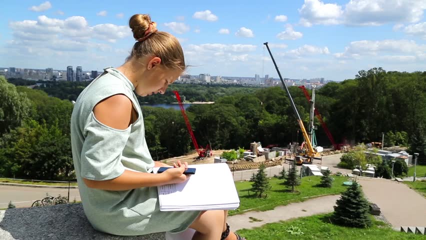 The girl is sitting on the step in front of the construction site.