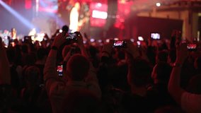 People taking photos or recording video with smartphones at live concert. Slow motion, steadicam shot