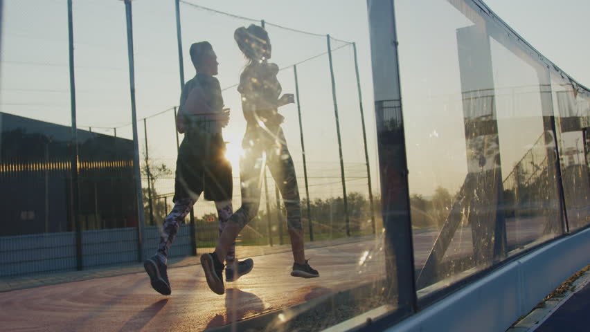 Running couple seen through a glass railing. | Shutterstock HD Video #1018387111