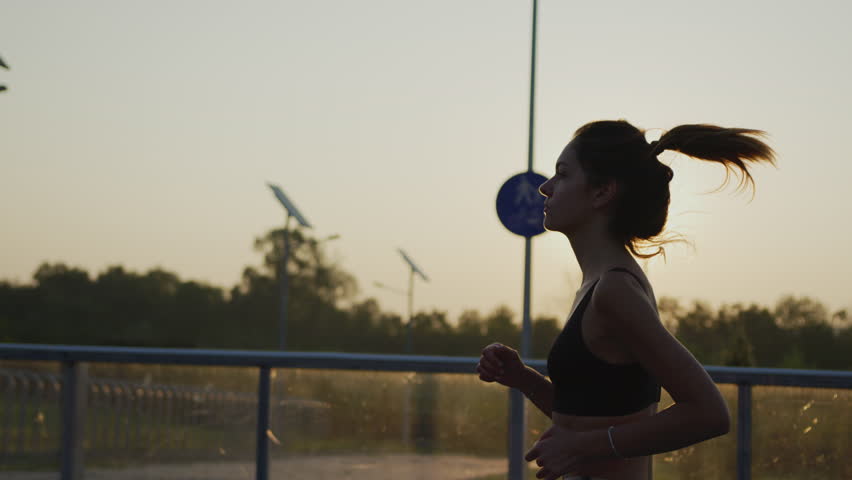 Side view of a girl jogging in the evening. | Shutterstock HD Video #1018387210