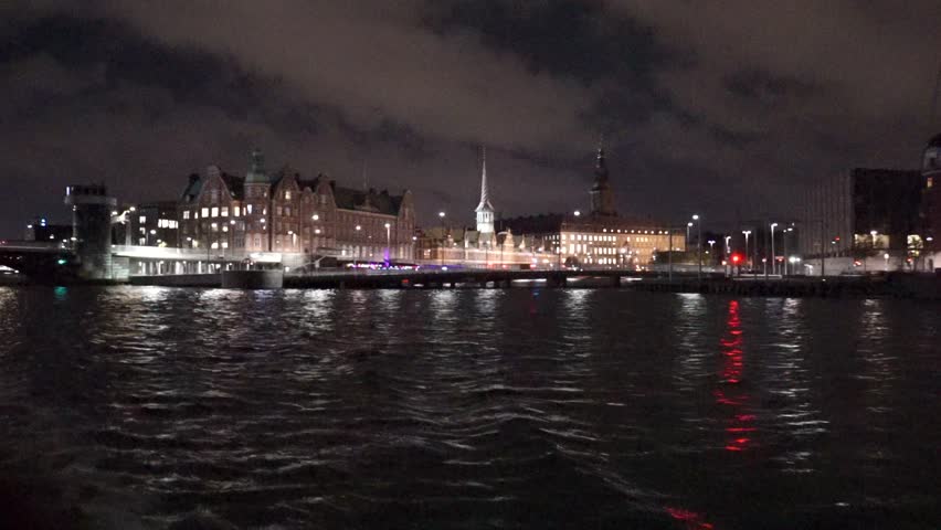 Beautiful Autumn Dark Night in The Port Of Copenhagen City, Denmark. Beautiful Background Of Water With Colorful Lights, Ships And Historical City. Water Night Tour.