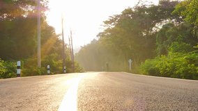 Asian men are cyclist riding a road bike in the forest with sunlight. Success, achievement, accomplishment and winning concept. video Slow motion