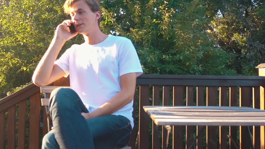 Man sitting down in a chair and talking on the phone in the summer