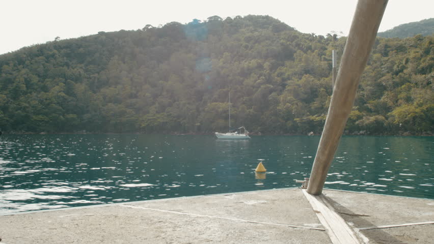 Small sailboat anchored at Lagoa Verde, Angra dos Reis, Rio de Janeiro, Brazil. Seen from a floating restaurant.