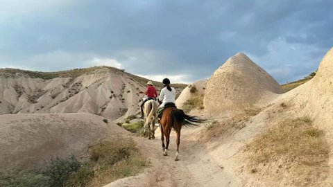 Horseback riding through the national Park in Cappadocia, Turkey, young woman riding horse at the mountains of Kapadokya