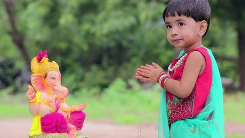 Little Indian girl child with lord ganesha and praying , Indian ganesh festival