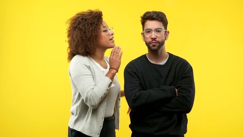 Young african american woman and caucasian man whispering gossip undertone, trying not to be heard