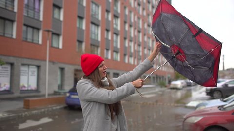 Young female sick woman, girl with umbrella standing. gust of wind pulls umbrella out of hand. girl holding umbrella. Bad miserable windy weather, high wind rain storm Flu cold disease health 4 K