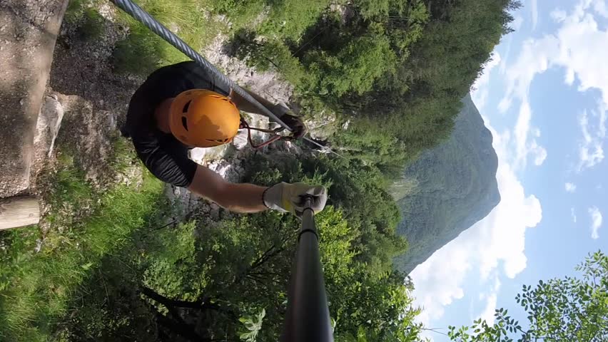 Man with beard canopying over the forest on zipline in Slovenia.