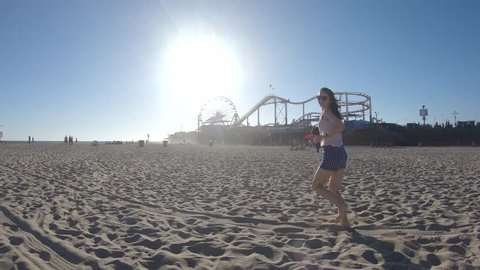 Happy young girl running on Santa Monica Beach, California, USA วิดีโอสต็อก