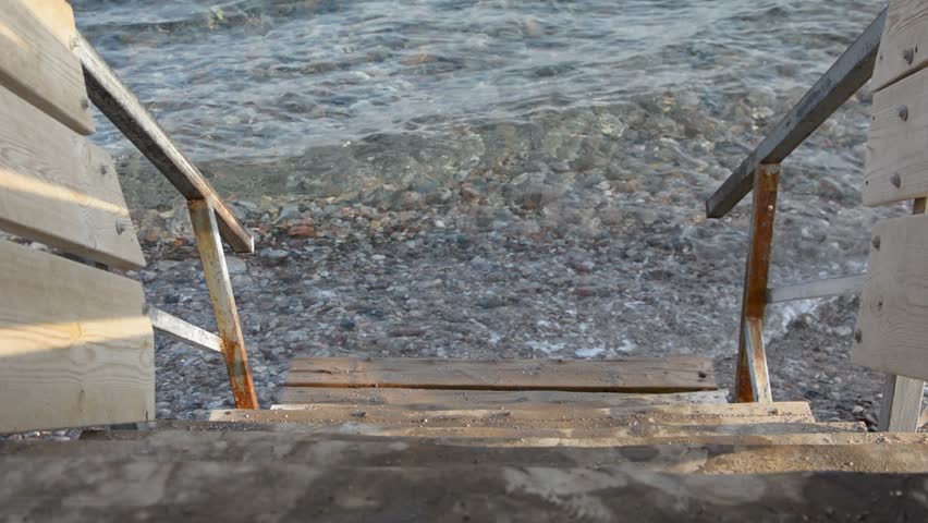 CLOSE UP: Old wooden porch with stair to the sea waves