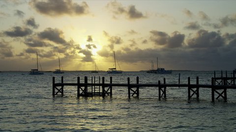 Tropical jetty and sailing boats on tranquil ocean in luxury Caribbean resort travel at sunrise Bahamas USA RED WEAPON